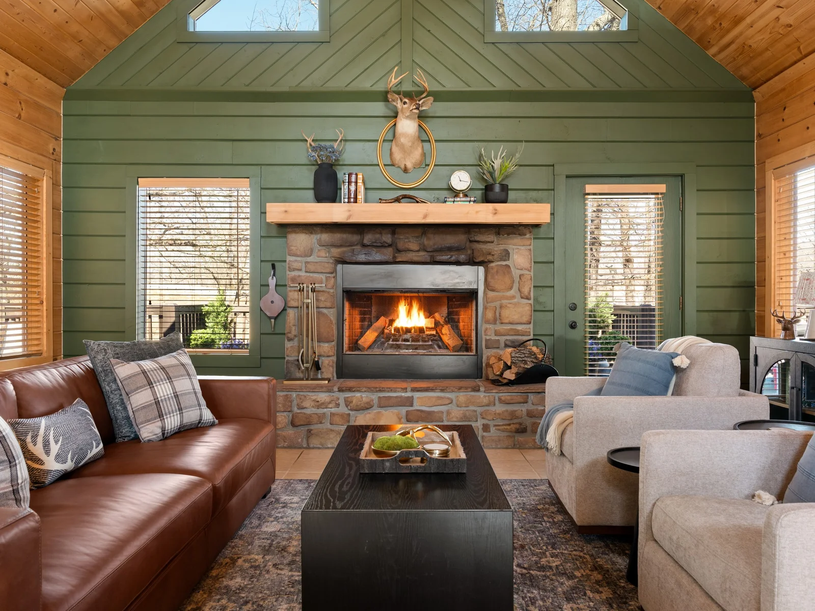 Stone fireplace with a crackling fire and deep green walls. Sink into the leather sofa and let the evening slow right down.
