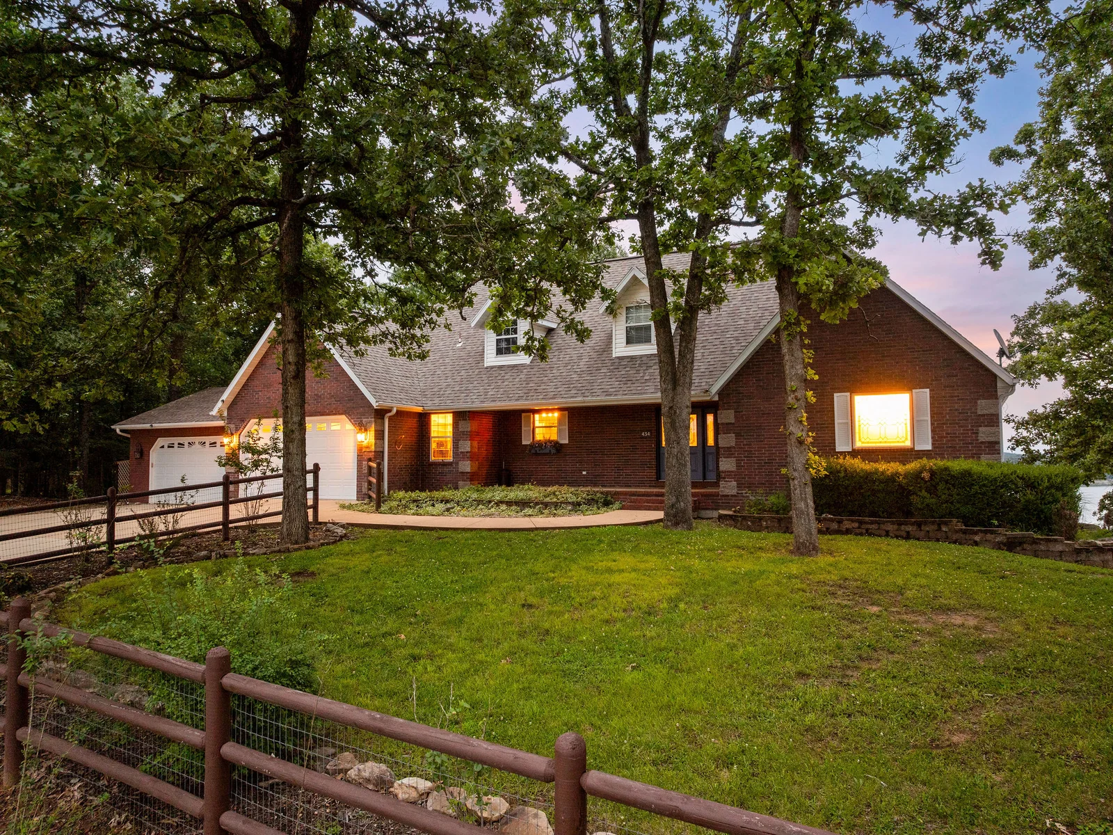 The house glows from inside at dusk — warm light in every window, the brick exterior going amber, the neighborhood quiet. You have got the whole place to yourselves.