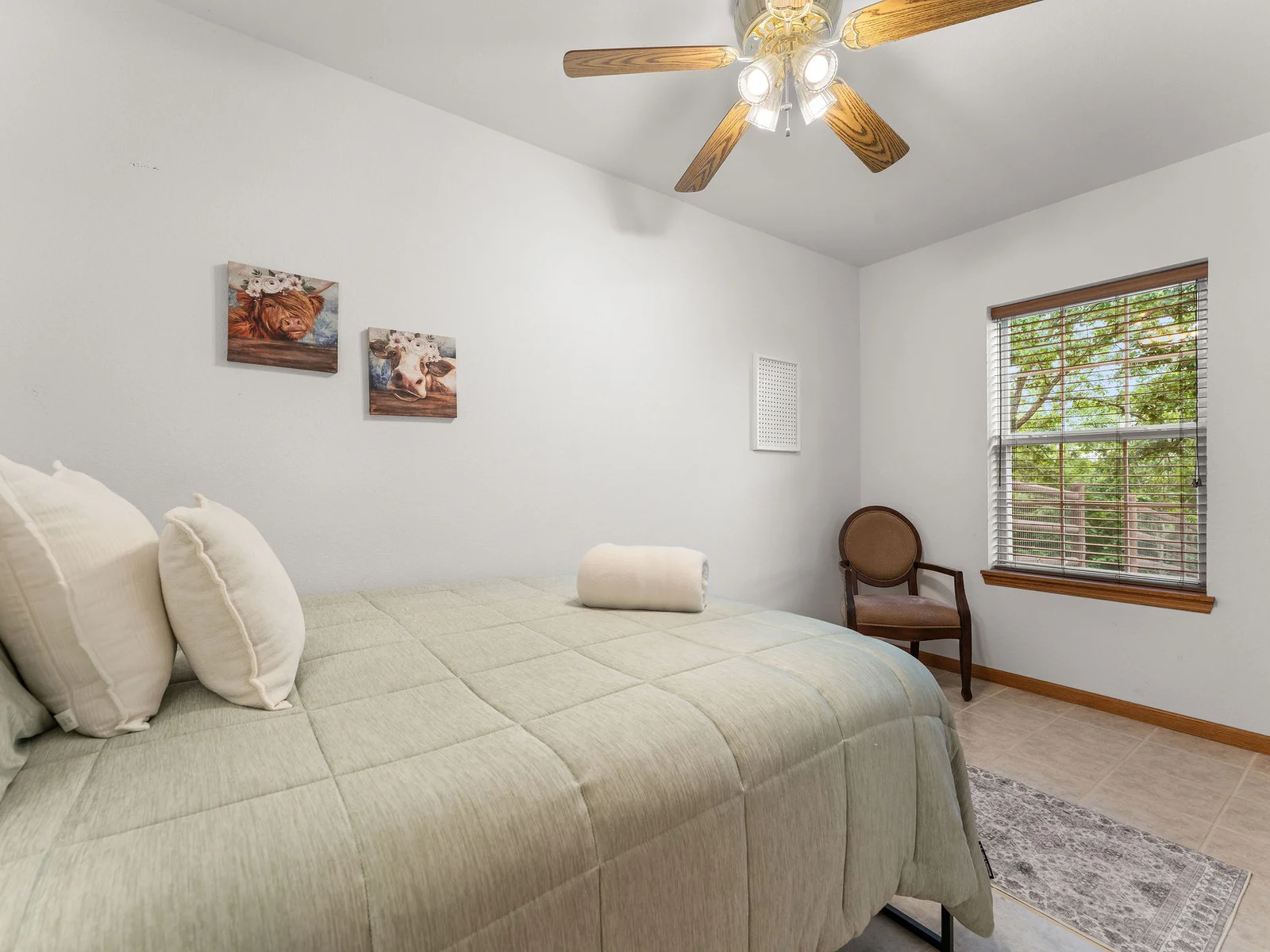 The third basement bedroom: a queen bed, tile floors, and the highland cow art that guests photograph every time. A small space with unexpected character.
