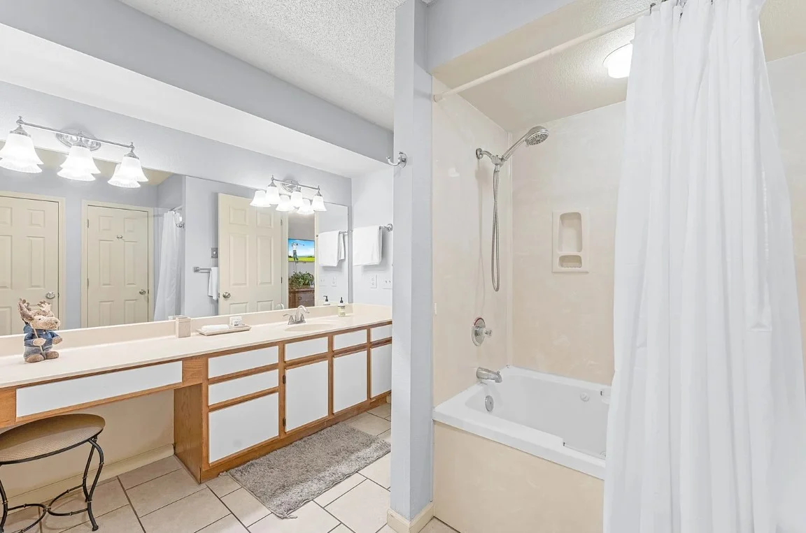 Spacious bathroom with shower-tub combo and bright lighting.