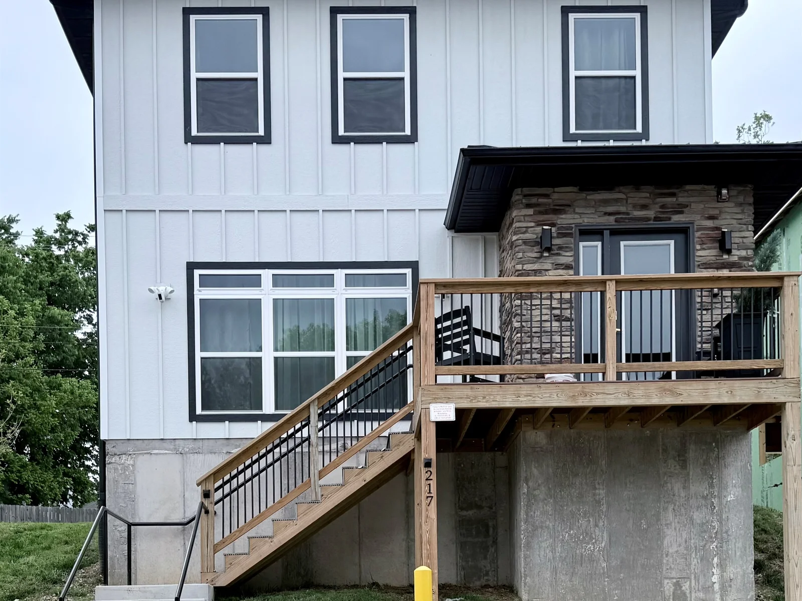 Front elevation of new vacation home with stone exterior at front door. Steps can be avoided by parking in rear parking space. Spacious with nine foot ceilings.