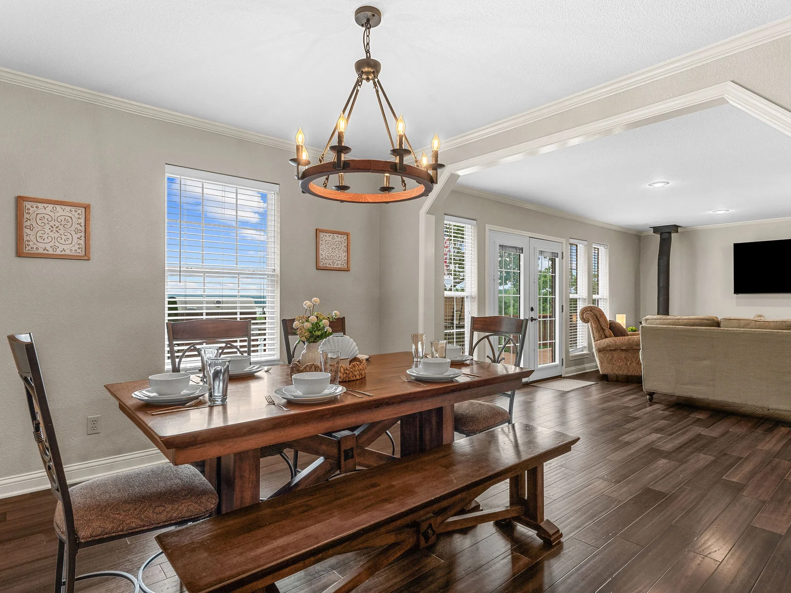 The dining table from the living room arch — room for ten, chandelier overhead, and a clear view through to the kitchen behind. This is where the group meals happen.