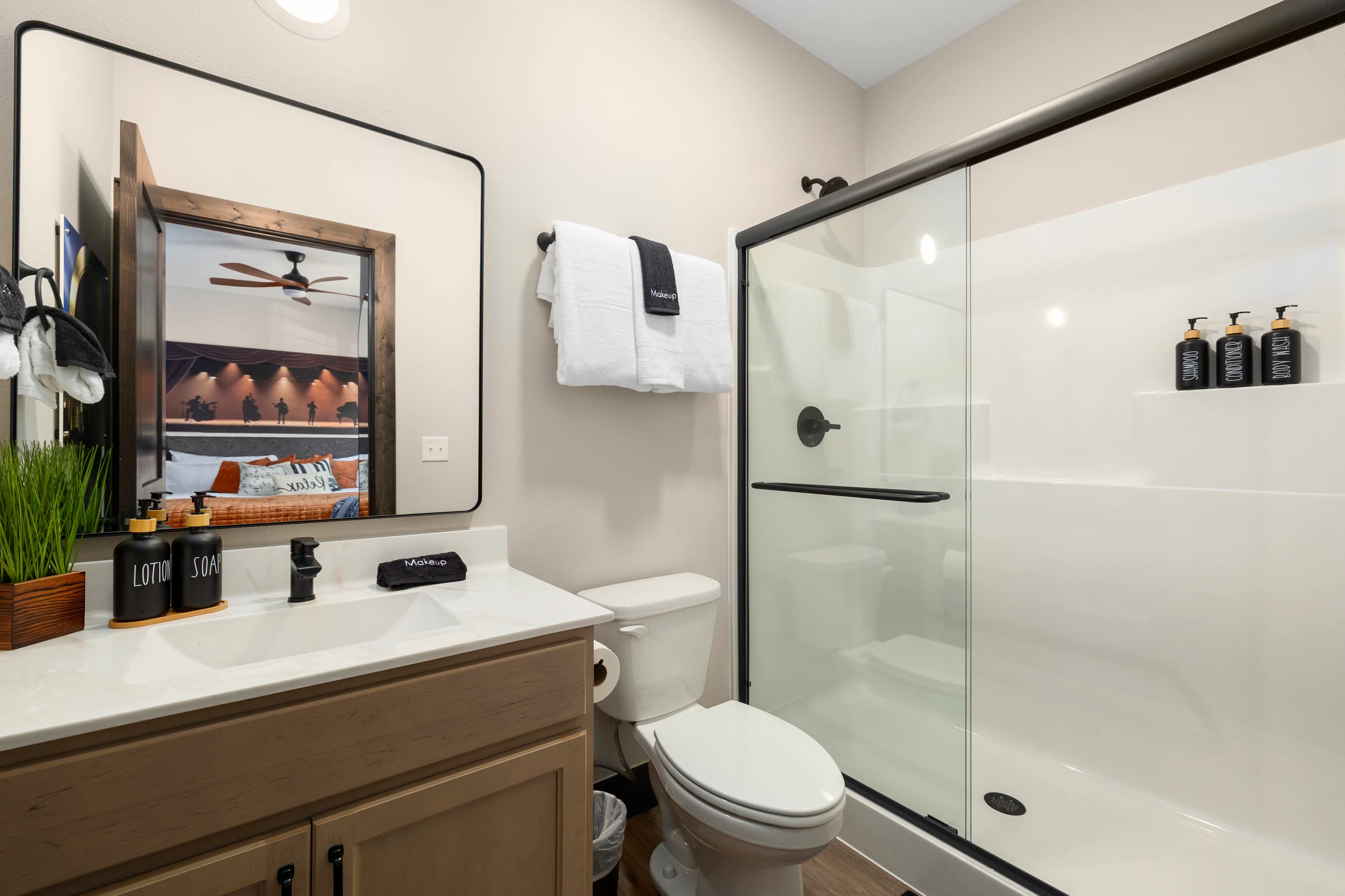 Walk-in shower, wood vanity, and a lit mirror in the ensuite.