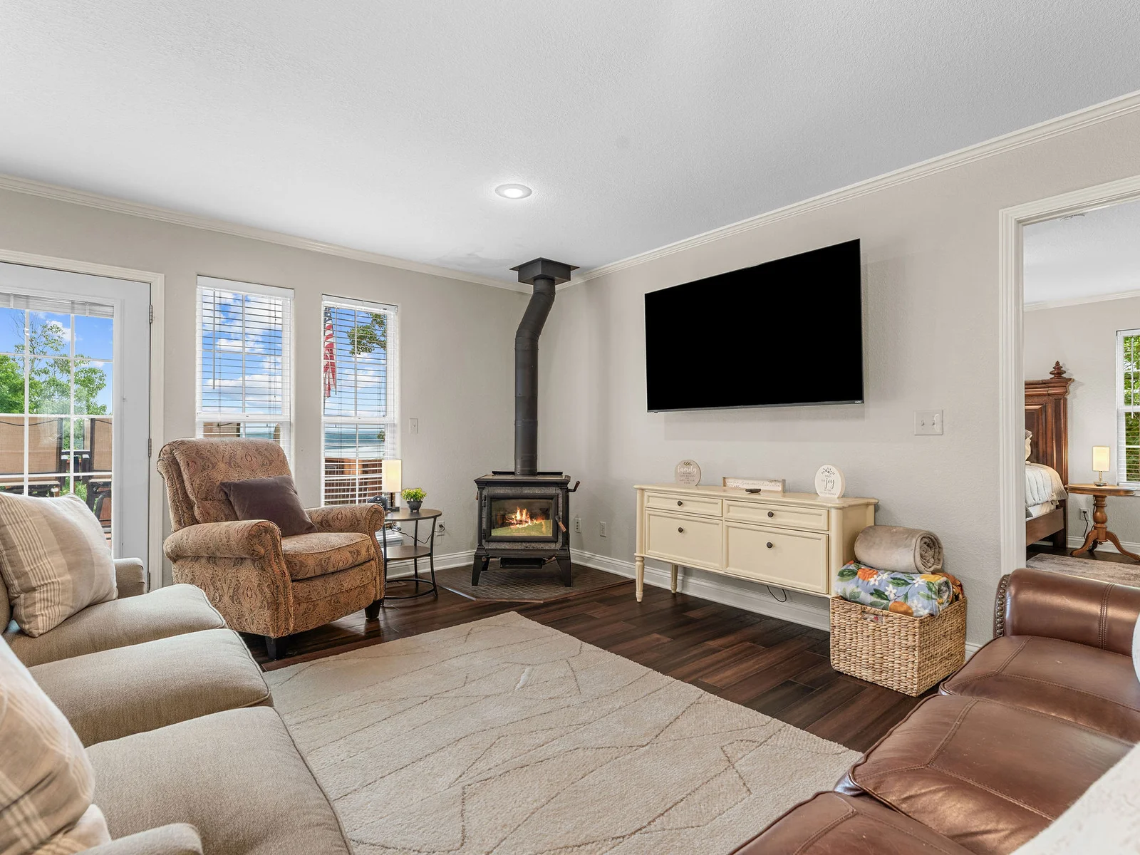 The wood stove glowing on a cool night, the lake catching the last light through the windows behind it — this living room earns its spot as the center of the house.