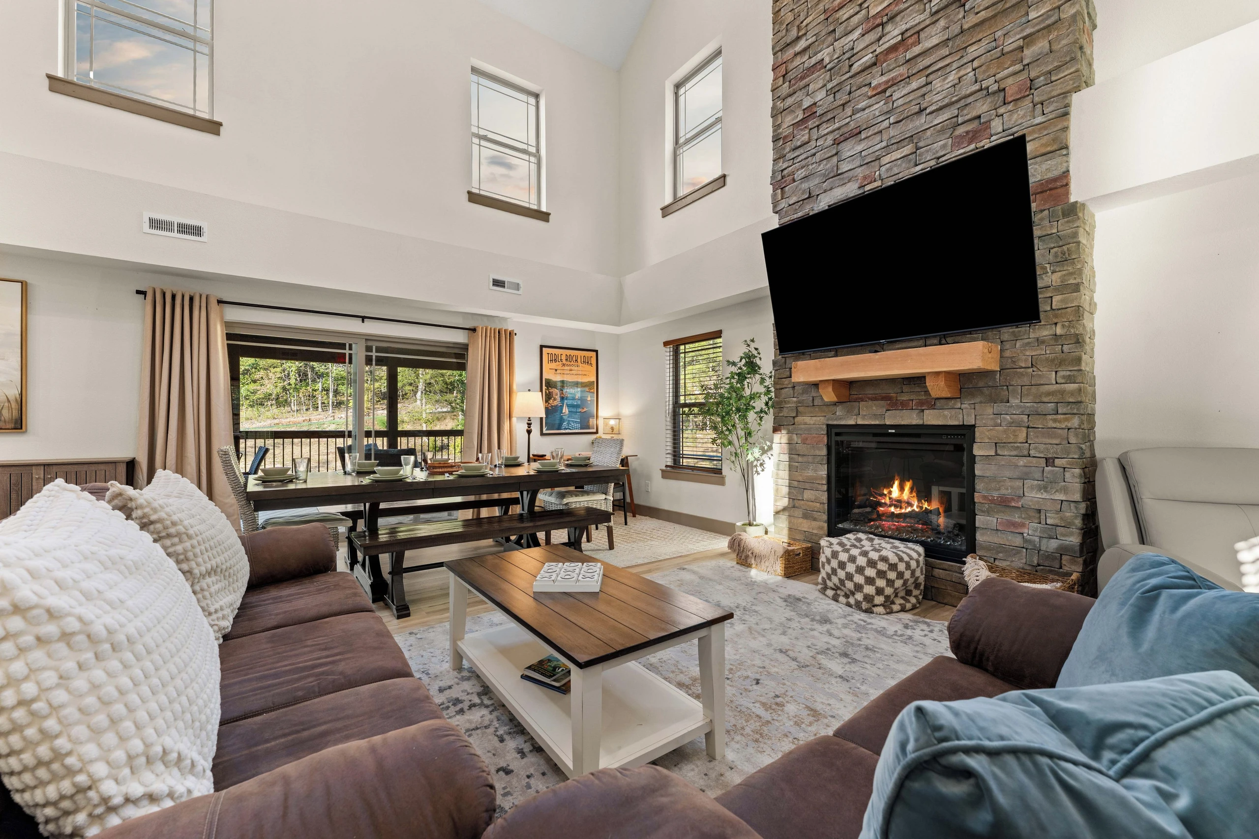 Living area has high vaulted ceilings, a lot of natural sunlight, electric fireplace, sliding glass door entrance to large deck overlooking the ravine and wooded mountain.