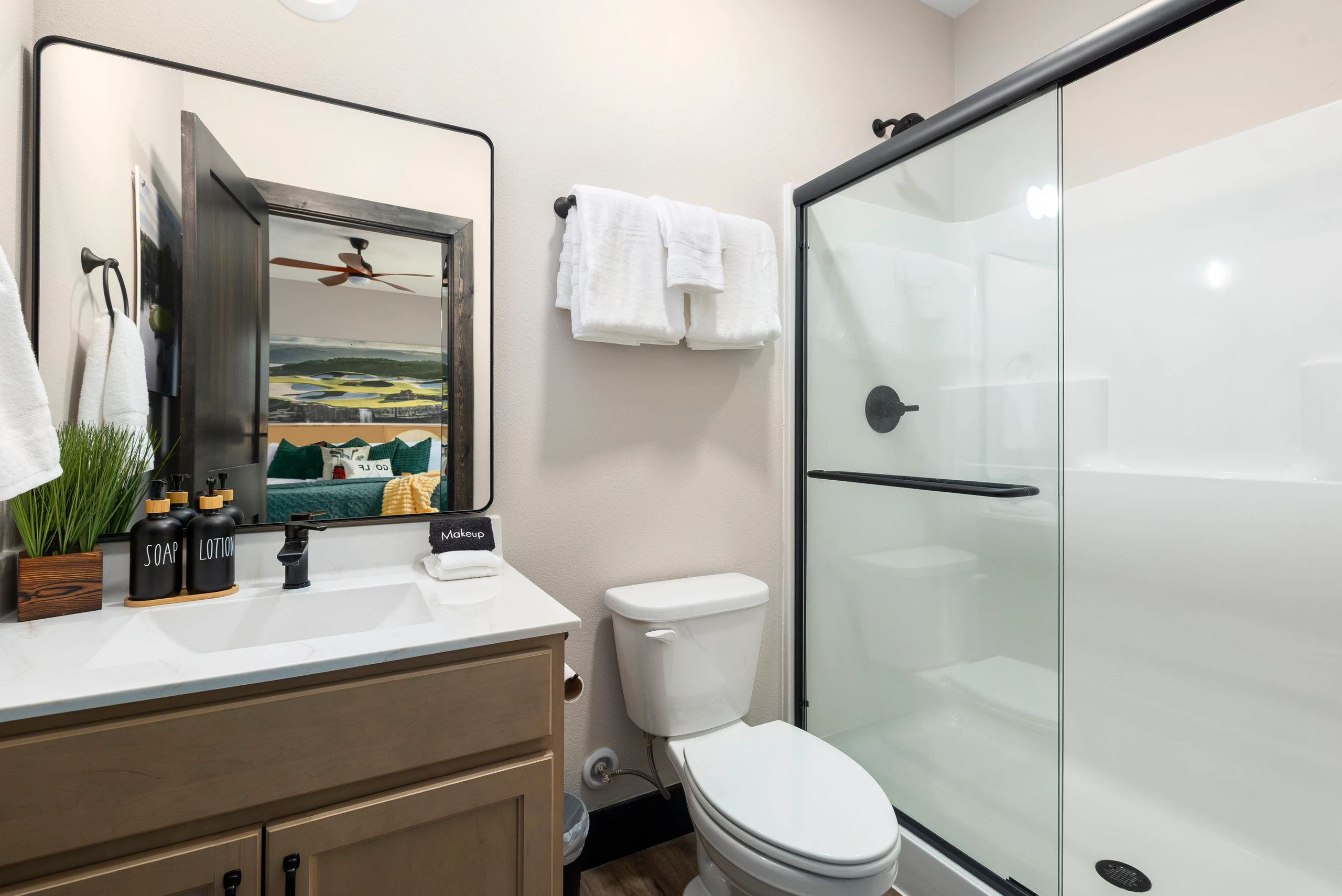 Lit mirror, wood vanity, and a spacious walk-in shower.