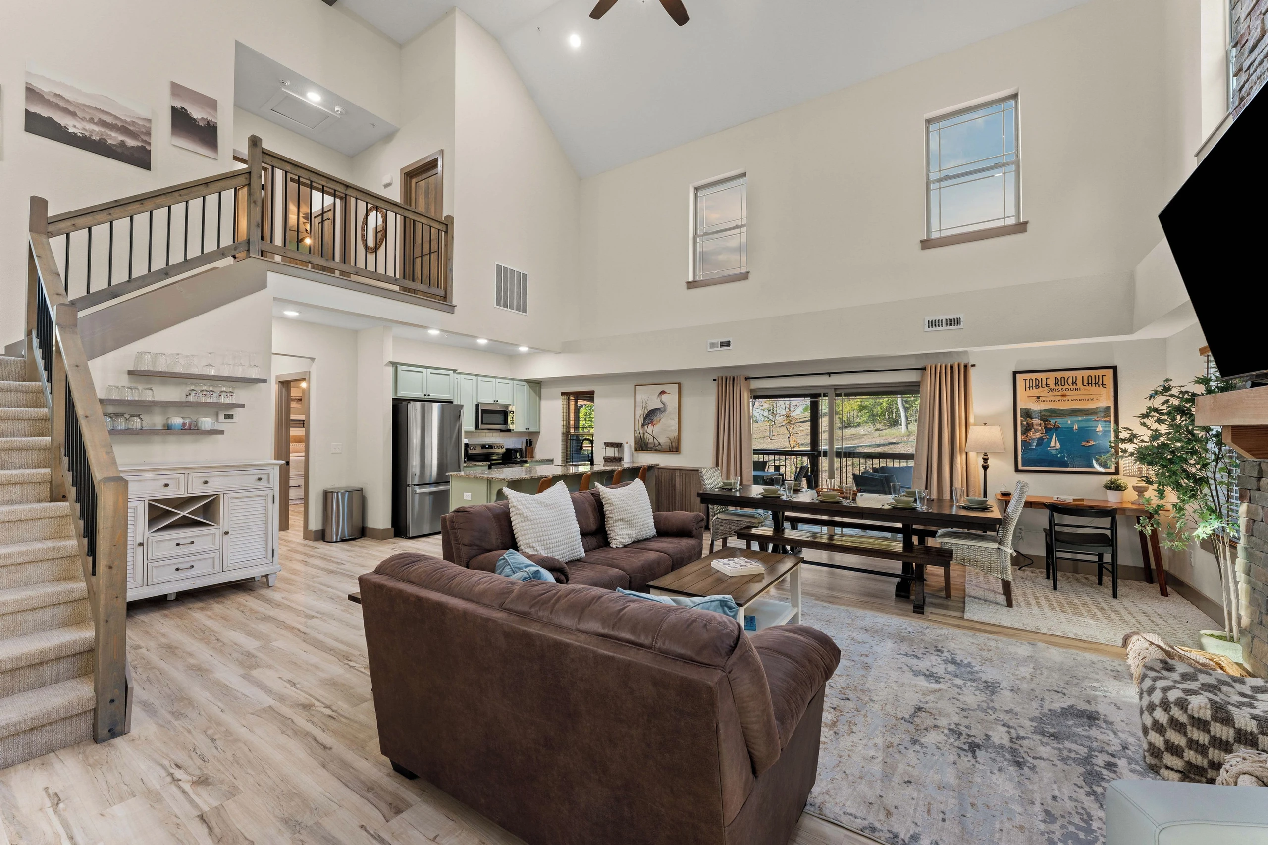 Open concept living room with sofas, chairs, desk, dining table and chairs and counter with 4 bar stools.