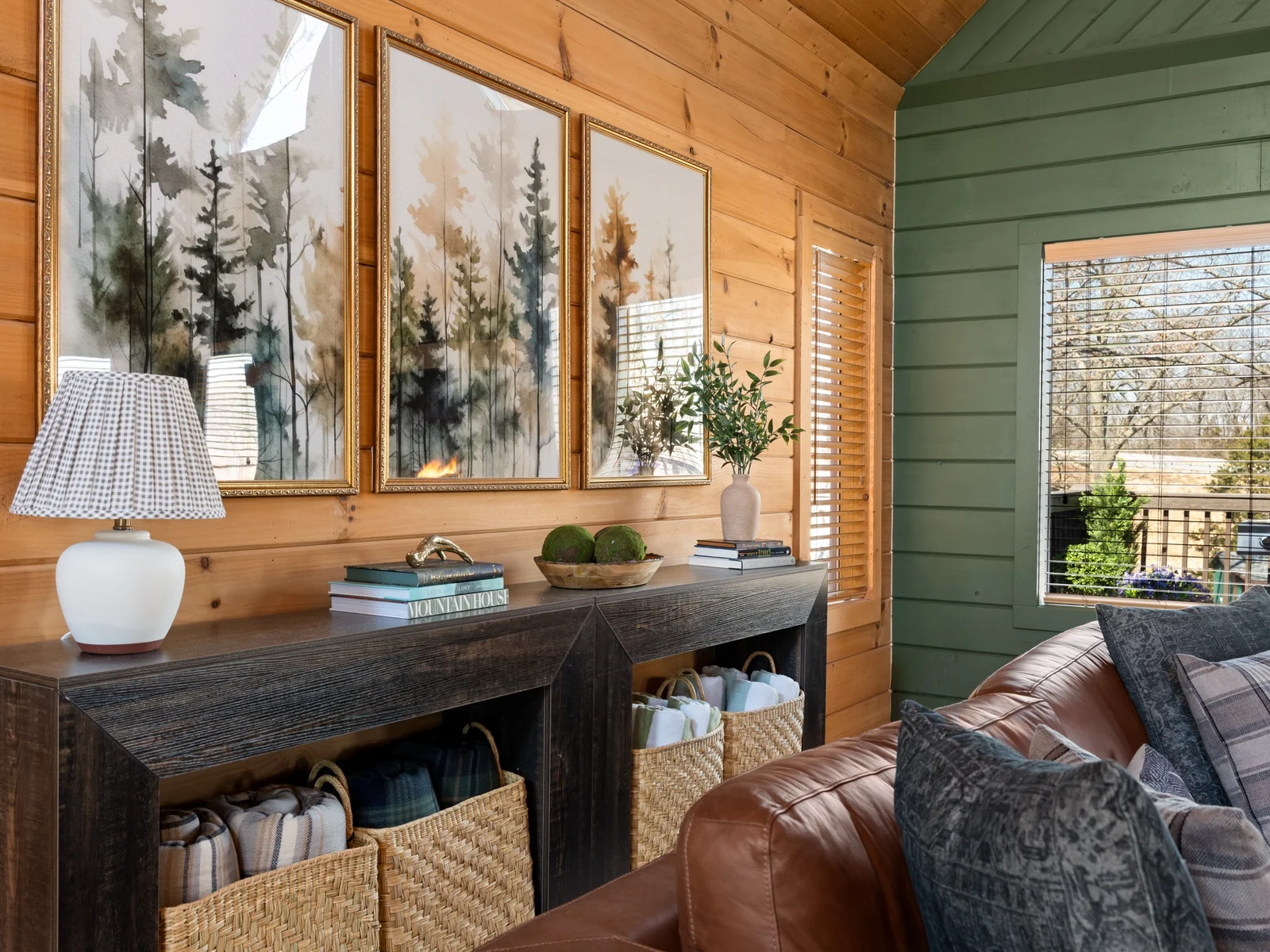 Console table with baskets of throw blankets beside the sofa. Forest art overhead and a blanket within reach for every movie night.