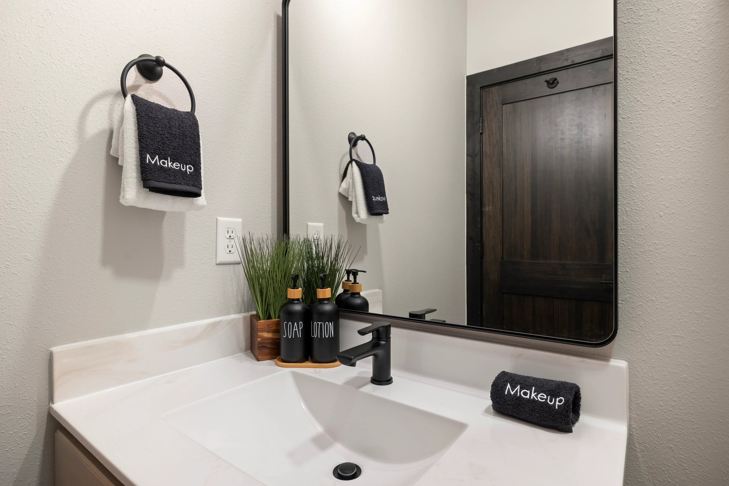 A lit mirror and black-fixture vanity just off the bedroom.