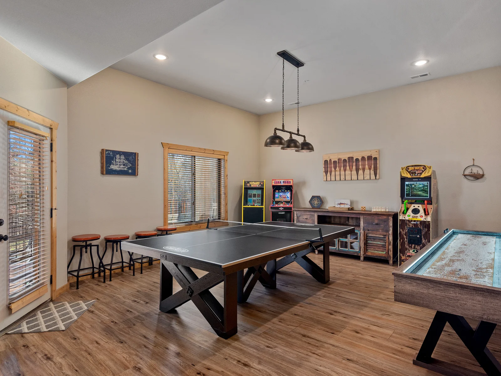 Lower level entertainment space with 3 arcade machines, ping pong, and shuffleboard