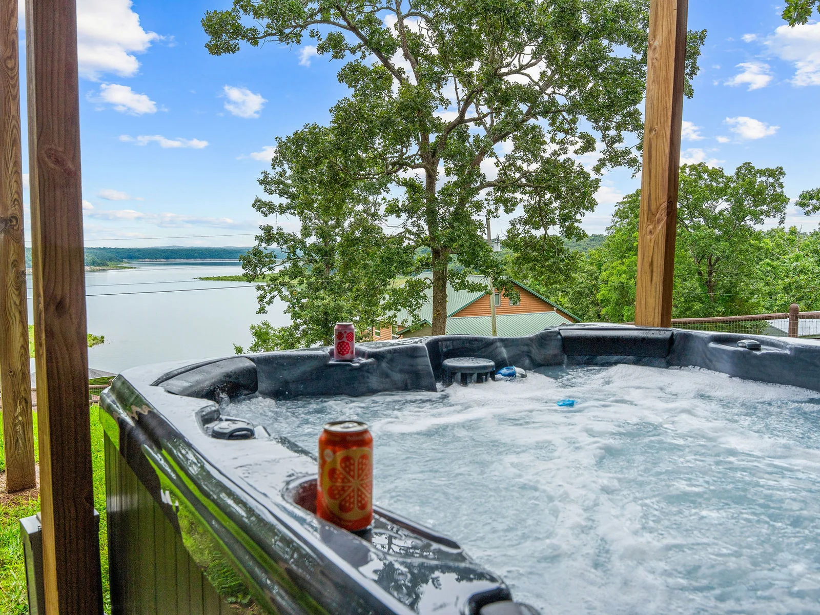 The hot tub with its own lake view, surrounded by mature trees and the covered lower patio. Pull the cover back, drop in, and do not come back up until dinnertime.
