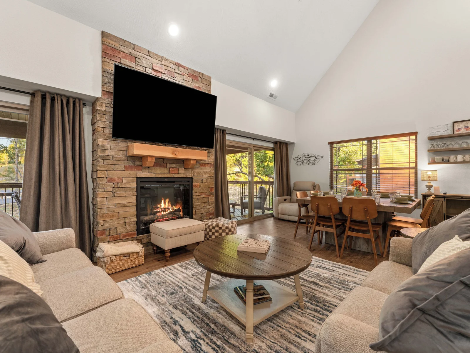 Living room with electric fireplace and two sets of sliding glass doors to enter the spacious outdoor deck.