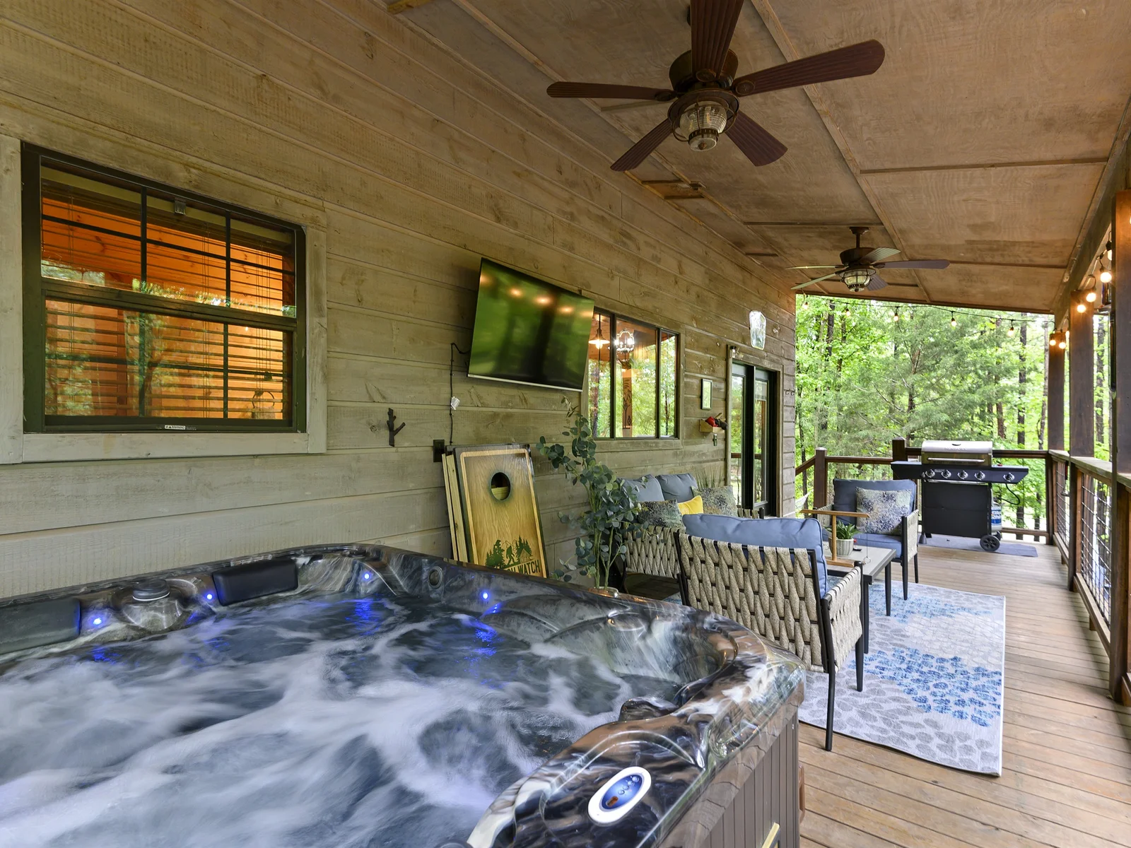 Serenity on the back deck: escape with outdoor seating, large smart TV, games, a bubbling hot tub, a sizzling grill, and a picturesque pond view.