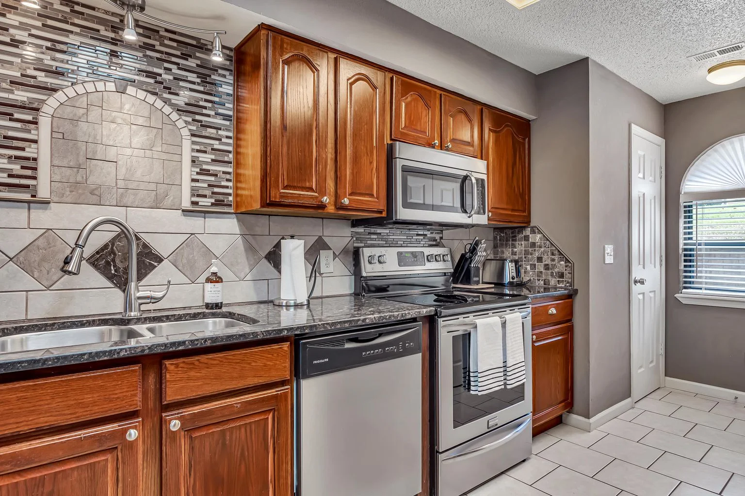 Updated kitchen with modern backsplash and stainless appliances.