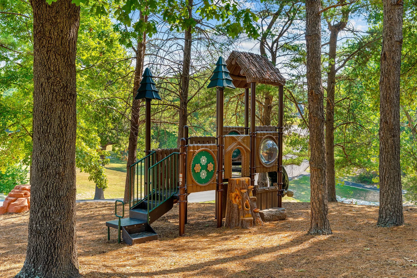 Shared playground tucked among the pines. Little explorers will love the climbing and the tree-stump steps.