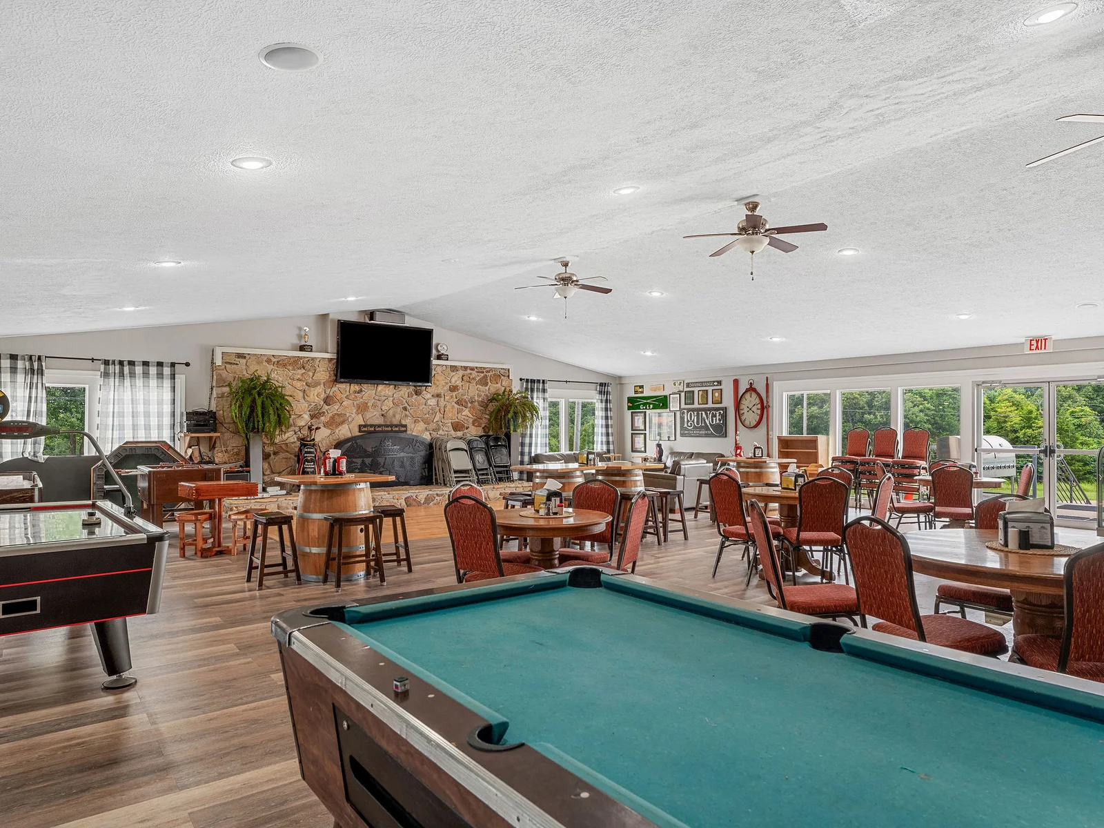 The community game room at Lost Woods Hideaway: a competition-size pool table, shuffleboard, a stone fireplace, and seating for the whole group.
